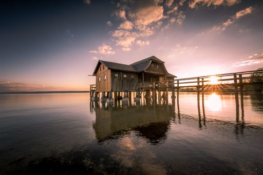 A beautiful view of a boathouse over Ammersee lake against the sunset sky in Bavaria, Germany