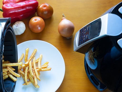 A top view of a person pouring out french fries from an air fryer