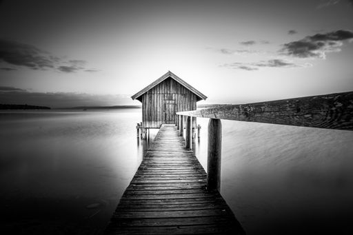 A grayscale shot of a boathouse over Ammersee lake against the cloudy sky in Bavaria, Germany