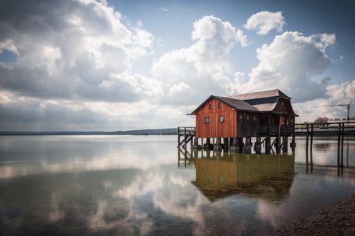 An old boathouse at lake Ammersee in Bavaria, Germany against a cloudy sky