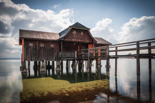An old boathouse at lake Ammersee in Bavaria, Germany against a cloudy sky