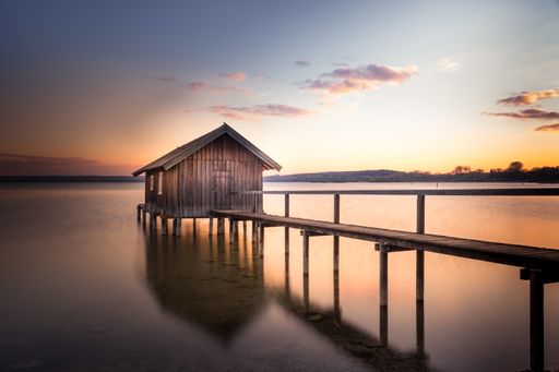 A beautiful view of a boathouse over Ammersee lake against the sunset sky in Bavaria, Germany