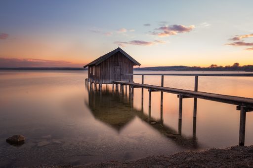 A beautiful view of a boathouse over Ammersee lake against the sunset sky in Bavaria, Germany