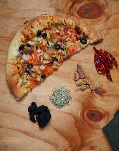A top view of freshly made tasty pizza with spices and other ingredients on wooden table