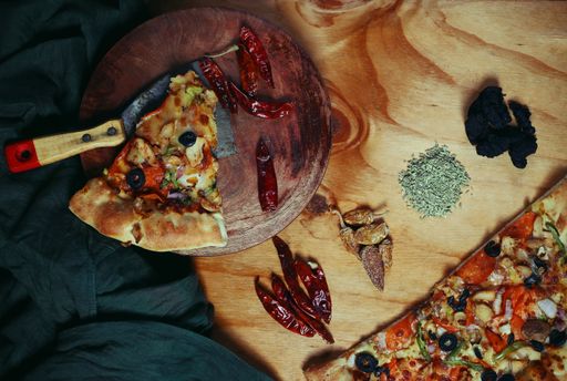 A top view of freshly made tasty pizza with spices and other ingredients on wooden table