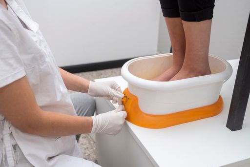 A female performing podiatry treatment with a wax machine in an aesthetic center