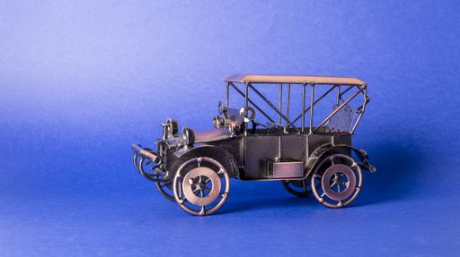 Homemade metal model - toy of an old retro car on a blue background