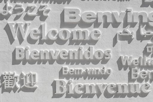 A word welcome written in several languages on a white wall
