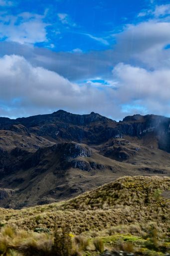 A vertical shot of mountains and a cloudy sky over it