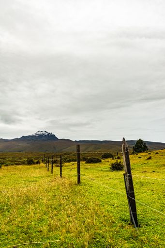 A mountain with snow on its summit with a cloudy sky over it