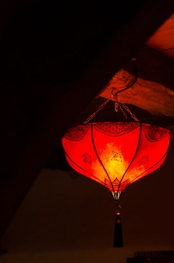 A vertical shot of a Chinese styled lamp hanging from an old wooden ceiling