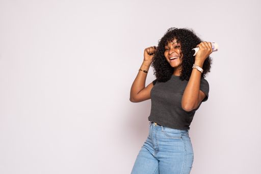 An attractive Black female holding some money rejoices