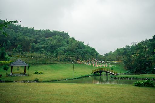 A view of a beautiful green area with pavillions and hills and a pond in the middle