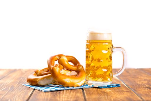A closeup shot of pretzel and beer for German Oktoberfest on a brown table