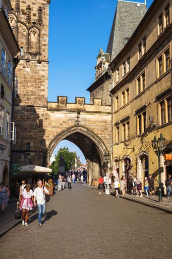 A vertical shot of tourists walking through the arch near the Charles Bridge in Prague, Czech Republic