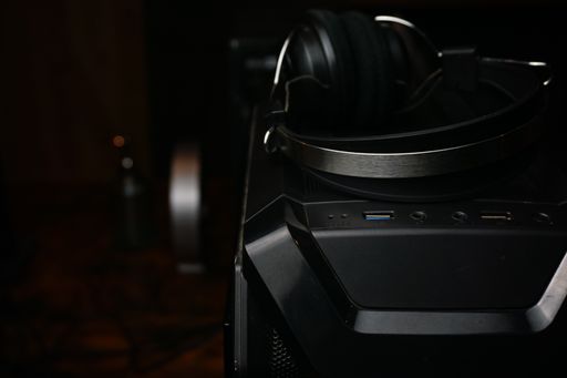 A closeup shot of black headphones on a black pc case