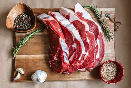 A top view shot of slices of raw meat on a wooden board with spices