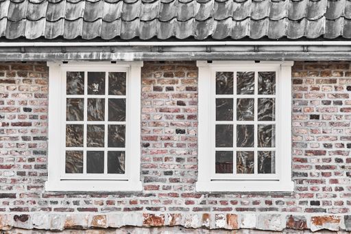 A closeup shot of an old brick house with white framed windows