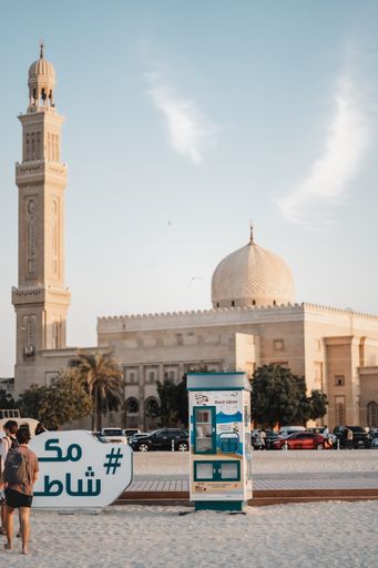 A vertical shot of a beautiful historic building and a book vending machine on a beach in Dubai