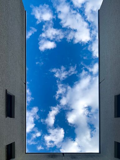 A low angle shot of a building under a blue sky with clouds