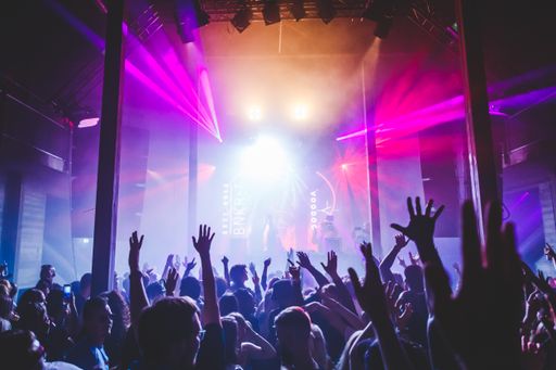 People cheering during an electronic dance music festival with awesome lighting from the stage