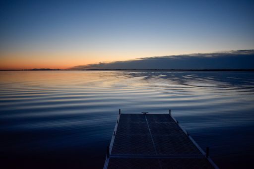 A mesmerizing view of sunset over a lake with reflection in water from a pier in Montreal, Canada