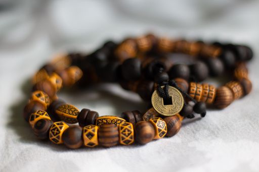 A closeup shot of an African bead unisex bracelet with bronze coin charm