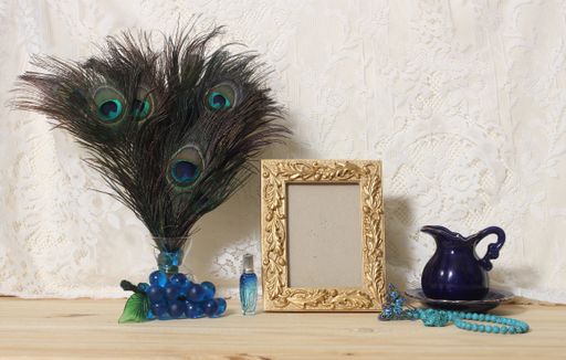 A Vase of Peacock Feathers With Blue Jewelry and Gold Picture Frame