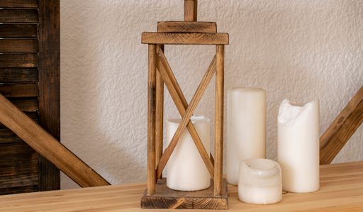 Old wooden decorative lamp and paraffin candles stand on shelf. Decor of modern apartment in retro style.