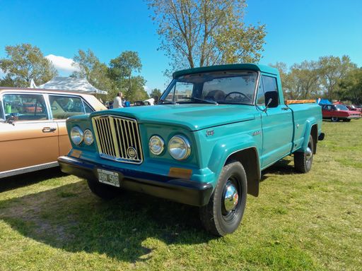 Old cyan Kaiser Jeep Gladiator pickup truck 1962 by IKA parked in the countryside. Nature green grass trees background. Sunny day. Classic car show