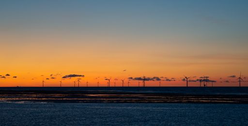 An aerial view of wind turbines near River Mersey at sunset