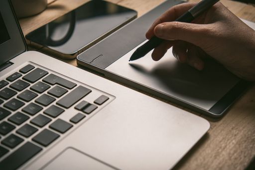 Graphic Designer working with interactive pen display, digital Drawing tablet and Pen on a computer. Smooth tracking shot with nice backlit lensflare.