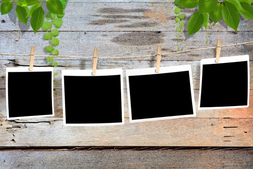 Blank black photos attached to a rope and a wooden background with leaves