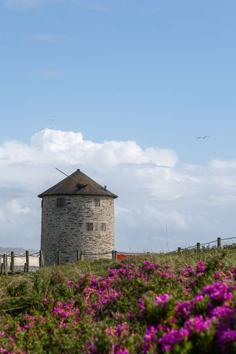 A beautiful view of a windmill on a hill by the sea under the blue sky
