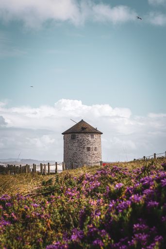A beautiful view of a windmill on a hill by the sea under the blue sky