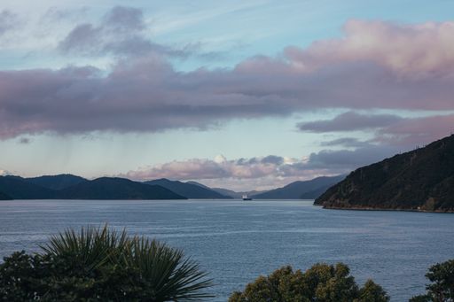 A mesmerizing view of the bay in New Zealand with hills under the cloudy sky at sunset