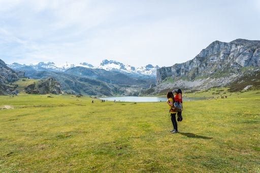 A beautiful shot of a mother with her child in her backpack at Lake Ercina in the Lakes of Covadonga, Asturias, Spain