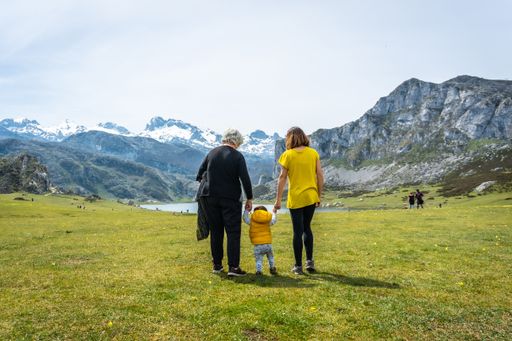 A back shot of three generations family visiting Lake Ercina on a sunny day in the Lakes of Covadonga, Asturias, Spain
