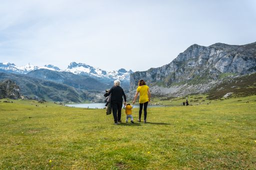 A back shot of three generations family visiting Lake Ercina on a sunny day in the Lakes of Covadonga, Asturias, Spain