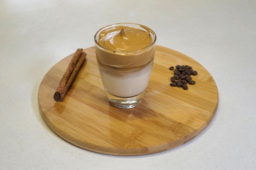 Whipped dalgona Coffee in a glass with coffee beans an cinnamon