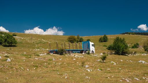 An old truck on the hill against a cloudy blue sky