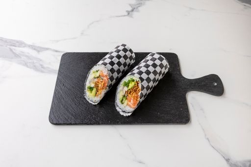 A closeup shot of sushi roll in black and white wrapper on a dark board