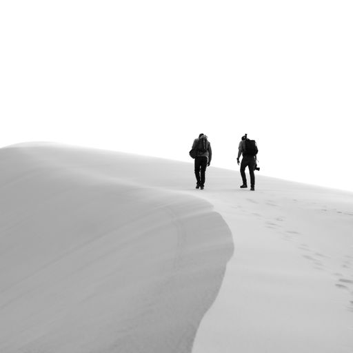 A grayscale shot of two people hiking in a desert