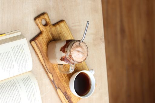 A vertical shot of a book with a cup of coffee coffee in coffee shop