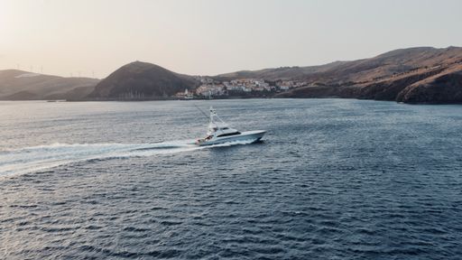 A sport fishing boat floating on a tranquil body of water, with majestic mountains in the background, providing a serene atmosphere
