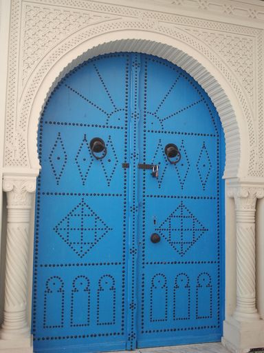 A vertical closeup shot of old blue wooden doors with ornaments in Tunisia, North Africa