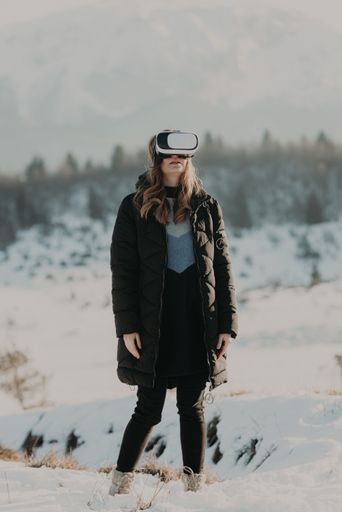 a vertical shot of girl in VR helmet standing in snow