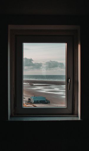A vertical shot from a window of a beach scene on a rainy day