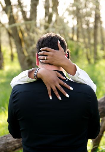 A vertical shot of a cute couple hugging each other outdoors during the engagement shoot