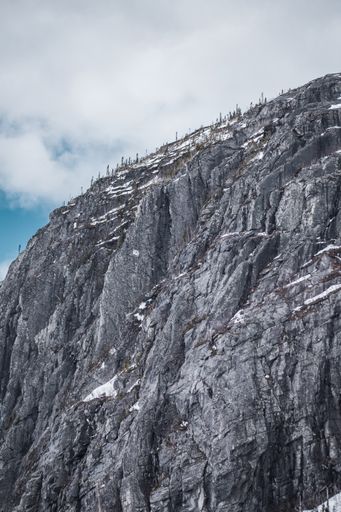 A vertical shot of a rocky mountain covered in white snow in Ile Perrot in Quebec, Canada